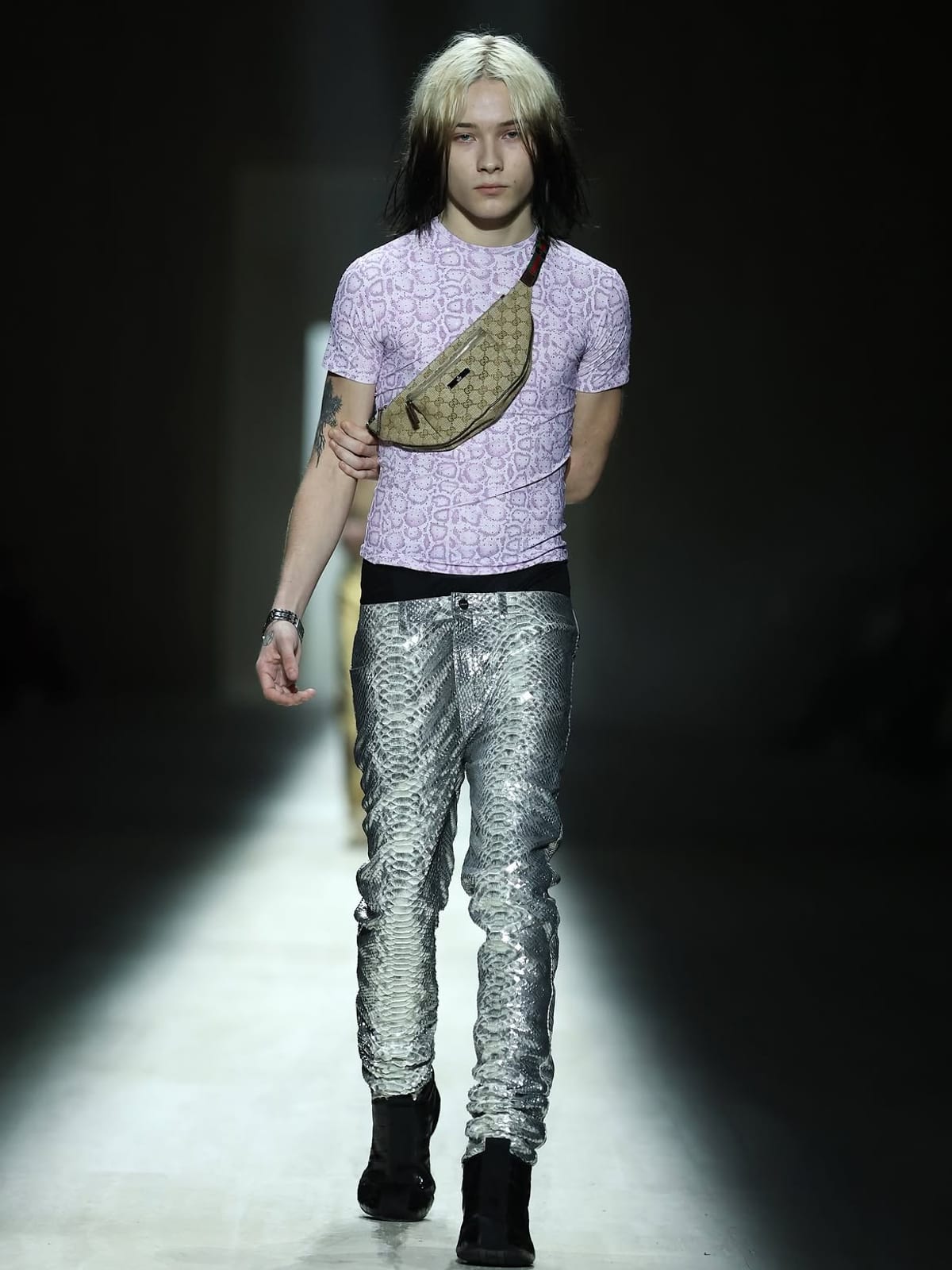 A model at Demna's first Gucci show in a lilac snakeskin-print tee, silver snakeskin trousers and a GG canvas belt bag worn across the chest
